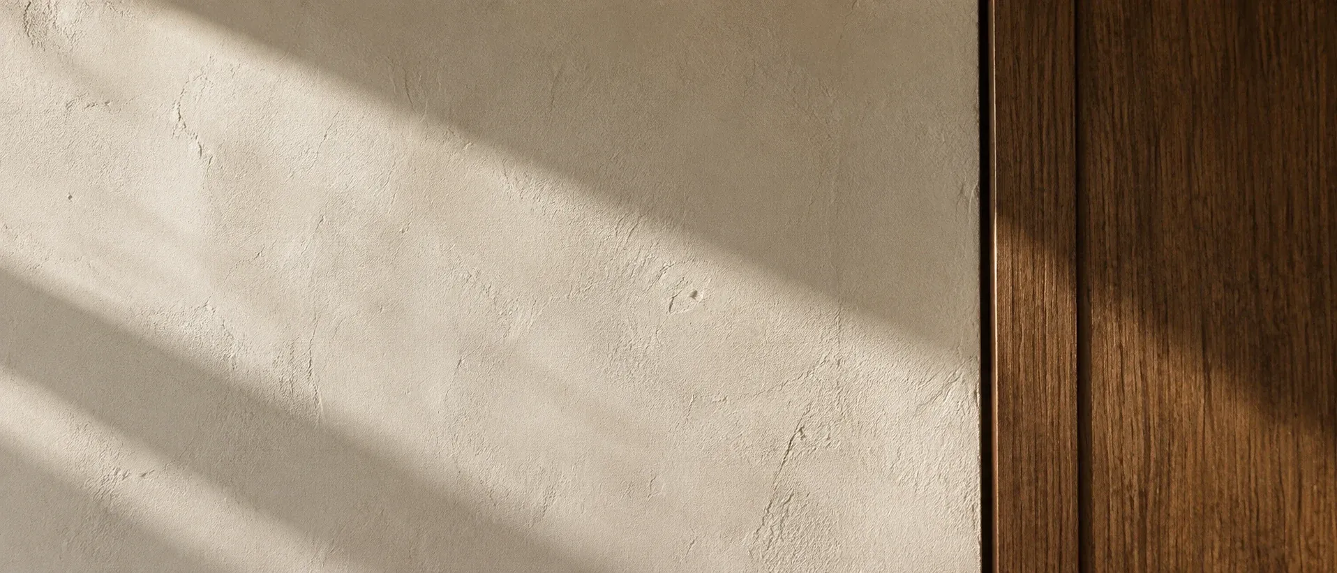 Luz da tarde sobre uma parede de reboco de cal ao lado de um painel de carvalho escuro